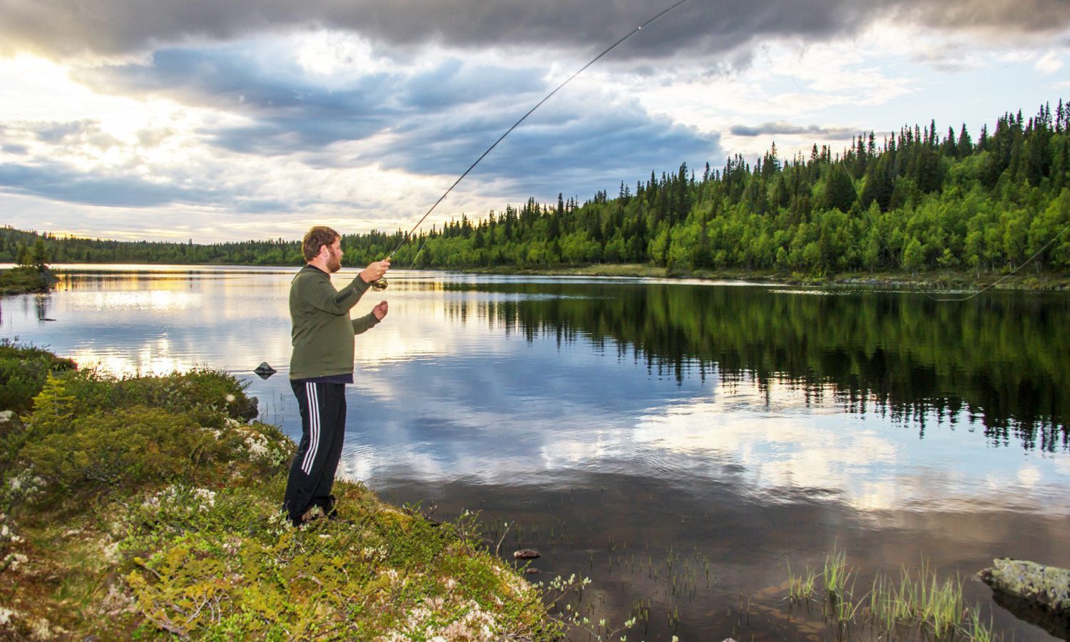 Bilde av mann som fisker i fjellvann