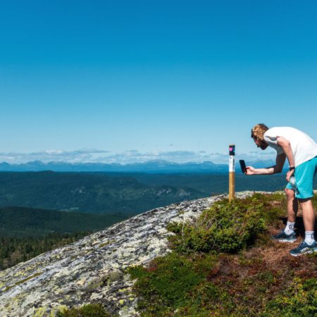 Bilde av en som scanner en stolpe på en fjelltopp